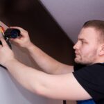 un homme travaillant sur un mur avec un tournevis