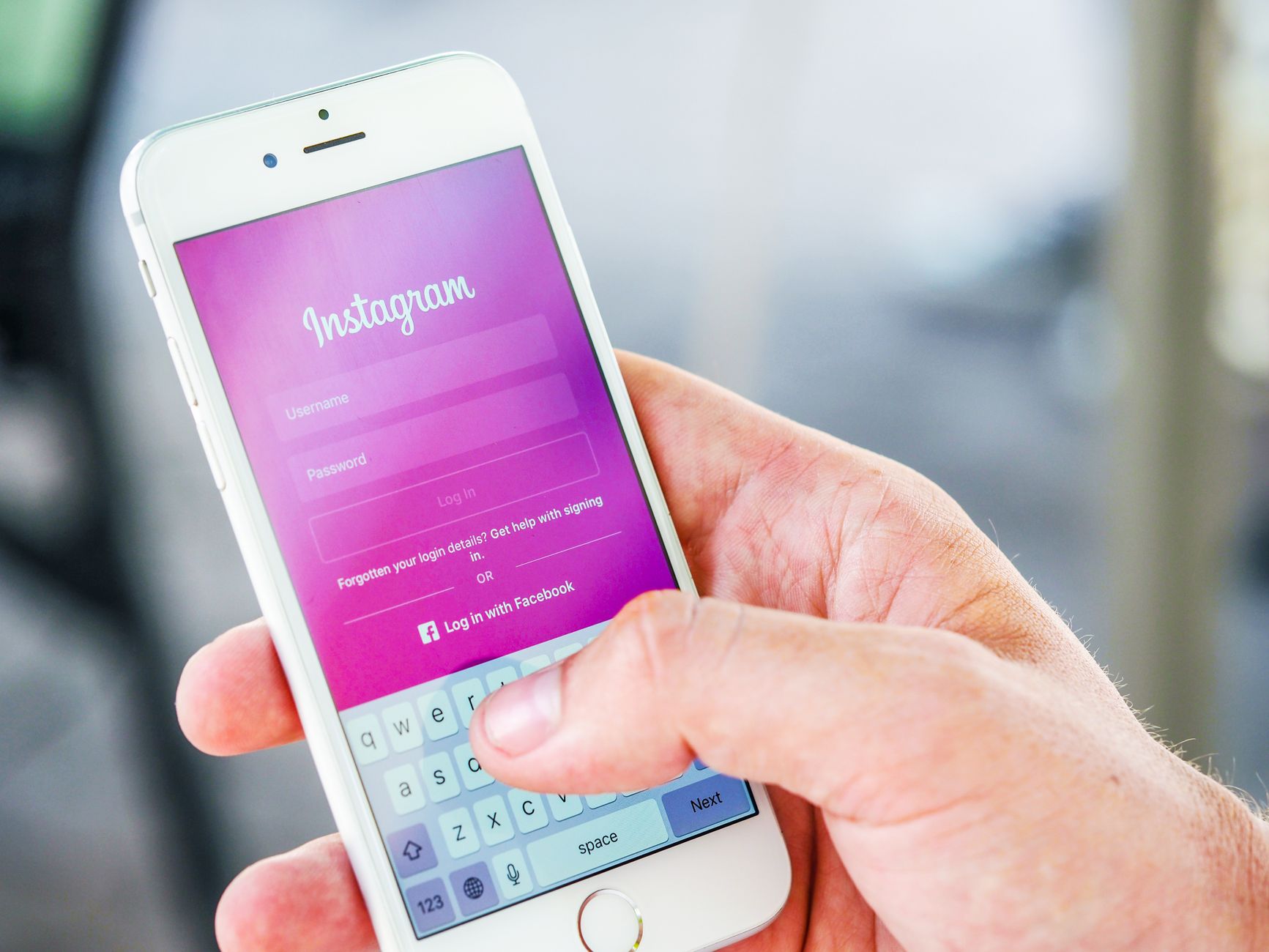 Gros plan d'une main tenant un smartphone affichant l'écran de connexion Instagram, mettant en évidence la technologie mobile.