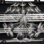 Lustre métallique moderne ressemblant à un pissenlit sur un plafond géométrique.