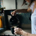 femme en t-shirt blanc tenant une tasse en céramique noire